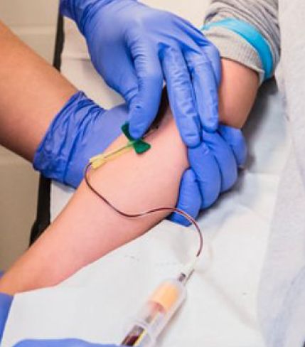 Infermera punxant amb una agulla d'ales al braç d'un pacient.