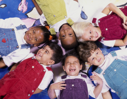 Uns quants nens de diferents races en una sala de jocs.