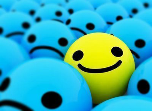 Una esfera amb una cara somrient enmig d'un grup d'esferes amb cares empipades.