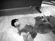 Un nen molt petit amb un peluix al llit.