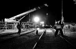 Persones treballant de nit sobre unes vies de tren.